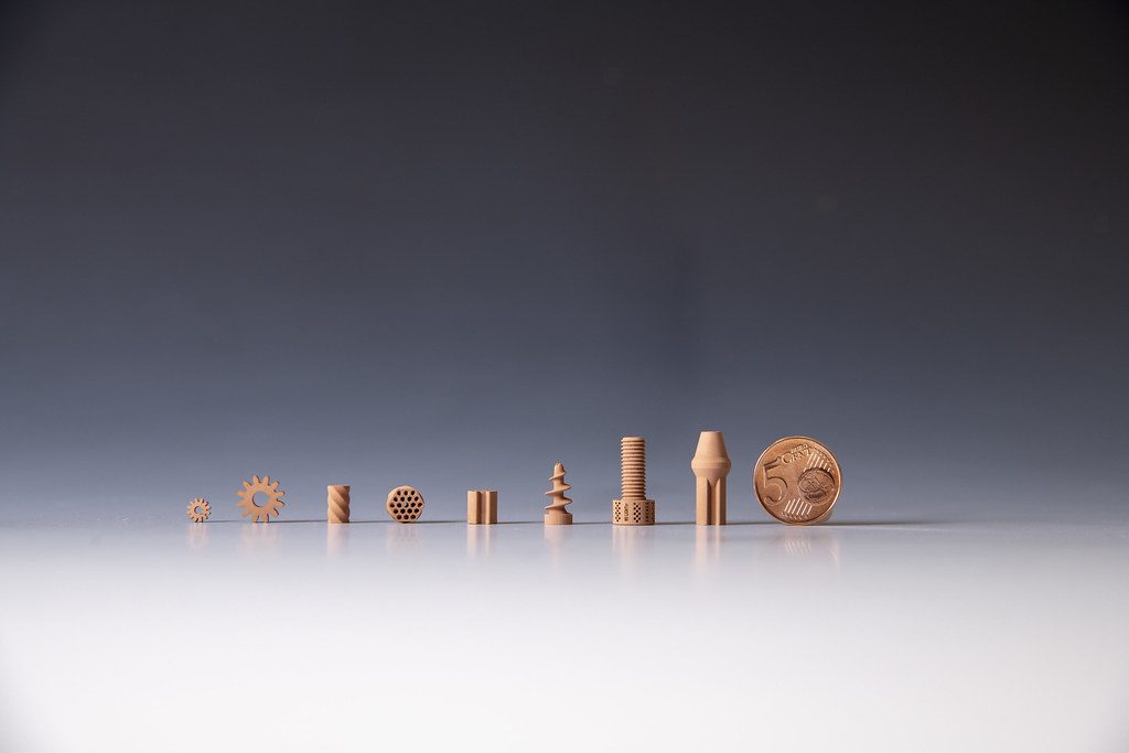 Micro additive-manufactured metal parts shown beside a coin for scale