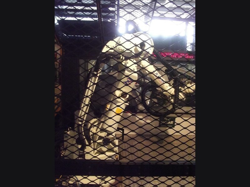 Industrial robotic arm behind safety mesh enclosure